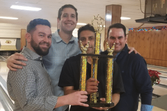 Four men hold trophy after winning the St Louis Lawyers Association Bowling Tournament